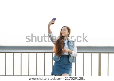 Excited young girl taking a selfie while standing at the bridge
