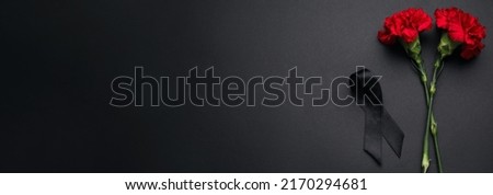 Black funeral ribbon and carnation flowers on dark background with space for text Royalty-Free Stock Photo #2170294681