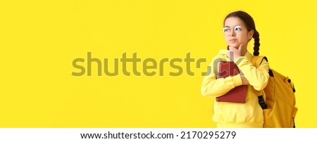 Cute little schoolgirl on yellow background with space for text