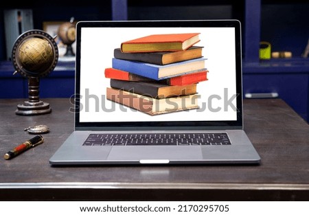 E-book library online education concept with laptop and stack of books on table.
