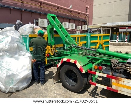 Employees with green trucks for transporting garbage. Urban waste recycling service Royalty-Free Stock Photo #2170298531