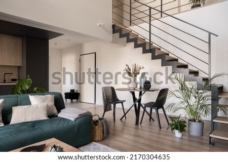 Modern, two-floor apartment with stylish living room with dining table, open to kitchen and stairs to next floor Royalty-Free Stock Photo #2170304635