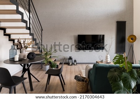Stylish decorated living room with stairs, big tv screen, cozy sofa and small dining table Royalty-Free Stock Photo #2170304643
