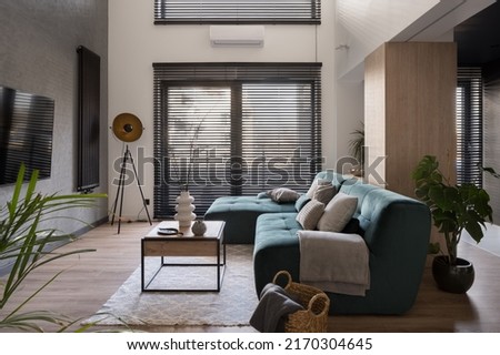 Modern and spacious living room with big windows with blinds, stylish furniture and decorations and wood decor Royalty-Free Stock Photo #2170304645