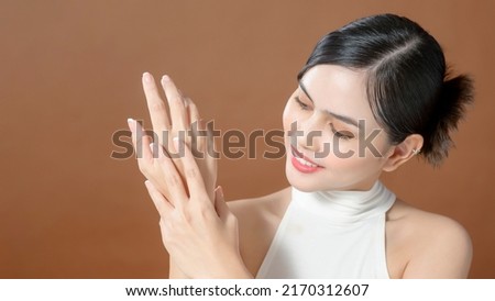 Close up young woman hand is applying cream over brown background , beauty skin care concept 