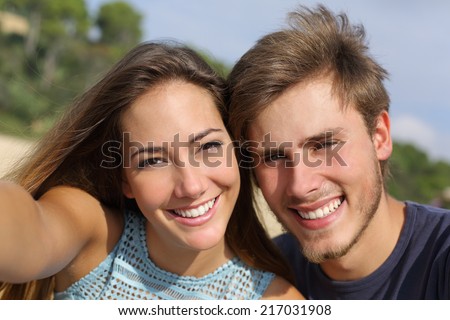 Couple photographing a selfie with the smart phone or digital camera outdoors in the mountain