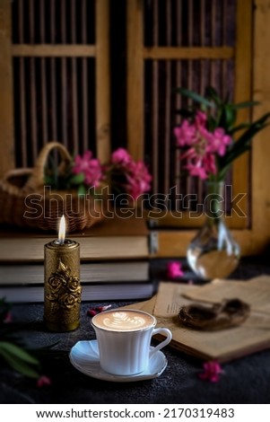 Still life coffee and candle with flower and books beside the window