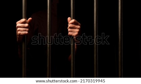hands of a prisoner behind prison bars on black background
 Royalty-Free Stock Photo #2170319945