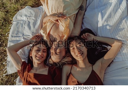 THREE GIRLS SITTING ON A COVER IN THE COUNTRYSIDE. 
