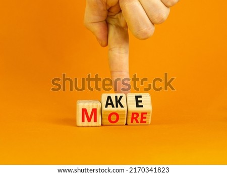 Make more symbol. Concept words Make more on wooden cubes. Businessman hand. Beautiful orange table orange background. Business, motivational quotes and Make more concept. Copy space.