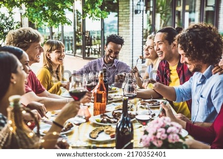 Happy multiracial family having bbq dinner party outside - Group of friends dining at garden restaurant - Young people enjoying lunch break together - Food and beverage lifestyle concept