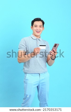 Minimal trendy portrait photo of Asian handsome and cheerful young man using credit card to make online payment, isolated on background
