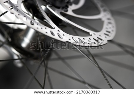 Hydraulic bicycle disk brakes, grey metal disc attached to bike wheel close up, effective popular mountain bicycle brakes. Hydraulic disk brakes on bicycle wheel, bicycle spokes gray background Royalty-Free Stock Photo #2170360319