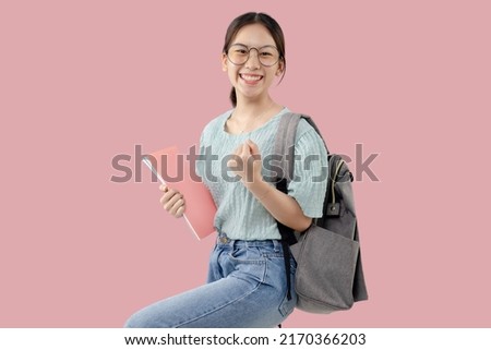 Happy Young Asian student girl standing over isolated pink background.