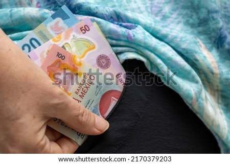 The woman pulls Mexican money, pesos bills from her pocket