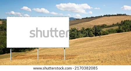 Blank advertising signboard in a italian rural scene with hills and cut wheat field - concept  with copy space for inserting text Royalty-Free Stock Photo #2170382085