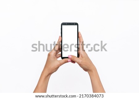 Mobile phone with white screen in female hands isolated on a white background. Blank with an empty copy space for the text. Template for the design. Mockup of a smartphone. A young woman takes picture