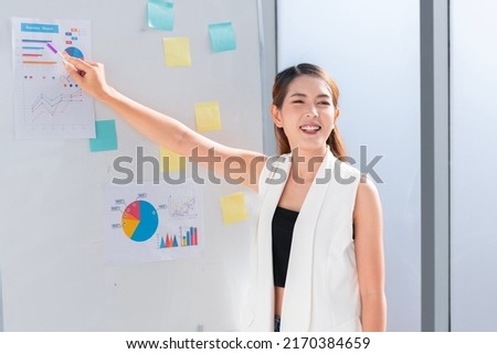 An Asian businesswomen is presenting his company performance report to his boss or group of male and female colleagues with confidence and professionalism.