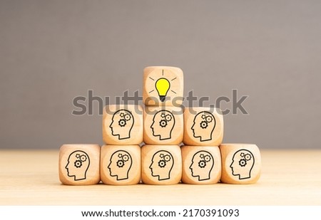 Team Creative idea or innovative idea concept. Brainstorming process. Wooden blocks with gear head icon stacked in pyramid stair shape and the top one with light bulb