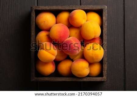 Heap of ripe apricots in wooden box on wooden table background. Top view. Close up. Royalty-Free Stock Photo #2170394057