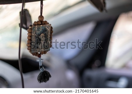 The icon amulet in the car of Nicholas the Wonderworker on a cord. The badge hangs conveniently on the rear-view mirror in the car. Translation: Seraphim of Sarov the Wonderworker Royalty-Free Stock Photo #2170401645
