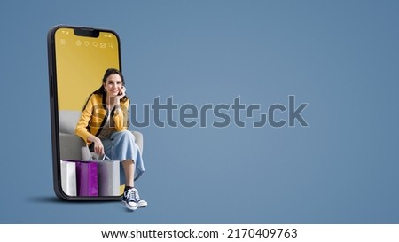 Happy young woman with shopping bags in a smartphone, online shopping and sales concept, blank copy space Royalty-Free Stock Photo #2170409763