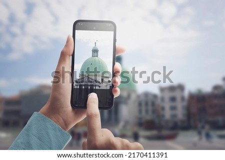 Tourist taking pictures of historical buildings with her smartphone, POV shot