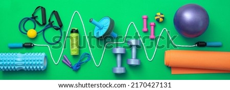 still life of group sports equipment for womens and cardiogram of jump rope, on green background. Fitness and healthy living, wellness concept. Royalty-Free Stock Photo #2170427131