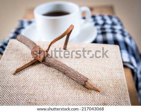Rustic pencil on notebook with coffee cup background