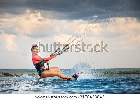 A young woman kitesurfer rides the waves doing a trick. Marine sports. kitesurfing Royalty-Free Stock Photo #2170433843