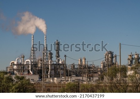 Oil refineries and coal-fired power plants are linked to global warming and climate change.  Pictured is oil refinery in Freeport, Texas with smoke stacks emitting carbon smoke.  Royalty-Free Stock Photo #2170437199