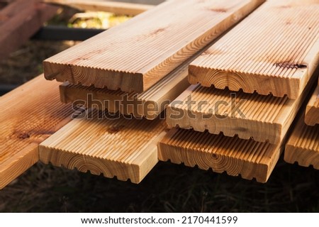 Stacked larch deck boards, close up outdoor photo with selective soft focus Royalty-Free Stock Photo #2170441599