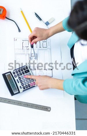 Top view photo of female engineer hand and calculator.