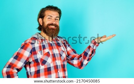 Smiling bearded man shows something on palm hand with copy space for product. Advertising. Discount.