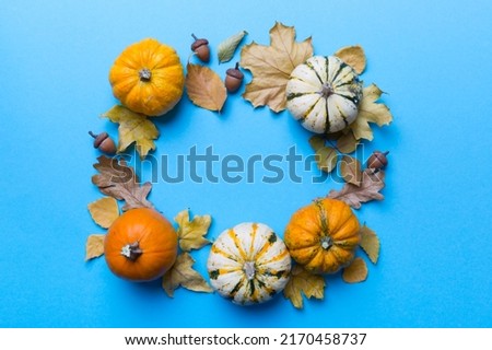 Autumn composition Pumpkins with fall leaves over coloredbackground. Top view with copy space.