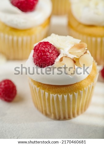 Close-up. Cream muffins topped with fresh raspberries and almonds. Isolated on white background. Recipe book, restaurant and home cooking. Advertising, banner, birthday invitation.