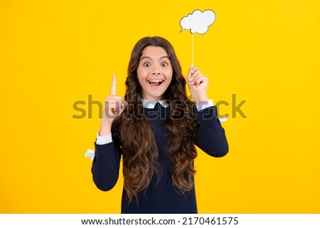 Excited face. Teen girl holding clouds empty space, thinking bubble, comment cloud over yellow background. Amazed expression, cheerful and glad.
