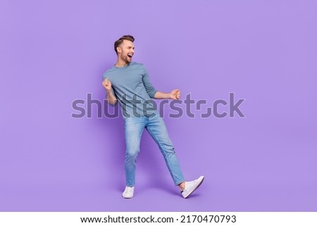 Photo of cool impressed guy dressed grey shirt dancing looking empty space isolated purple color background