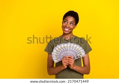 Photo of minded positive person look interested empty space hold cashback isolated on yellow color background