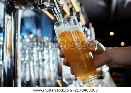 Pouring beer into a mug in a beer bar close-up. Beer bottling in the restaurant. The bar counter. Royalty-Free Stock Photo #2170483203