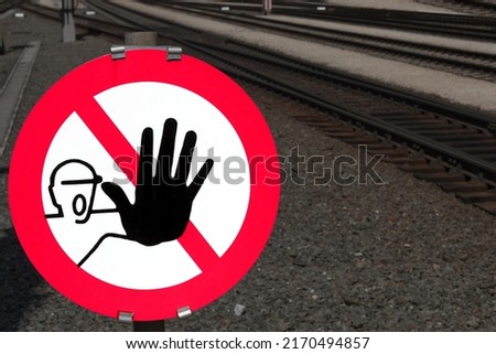 Close up of signal color red danger stop sign with black hand as a clear indication prohibition not to enter railroad tracks and railway facilities as a concept of danger in railroad traffic