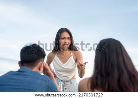 A young woman confronts and scolds her cheating boyfriend on a date with another woman at a cafe. A public confrontation. Royalty-Free Stock Photo #2170501729