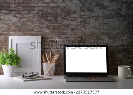 Laptop computer, picture frame, houseplant and stationery on white table. Modern workplace.	