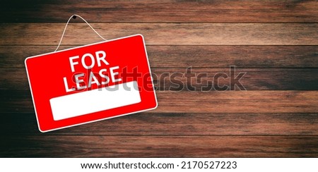 FOR LEASE red sign with white word on empty wooden background, advertising template. Label for real estate hiring hanged on wood surface, marketing from agent. Copy space