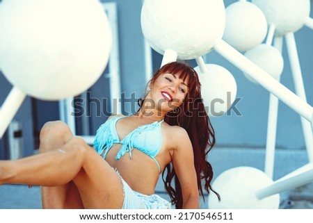a girl in a swimsuit poses with plastic balls in the form of human dna.