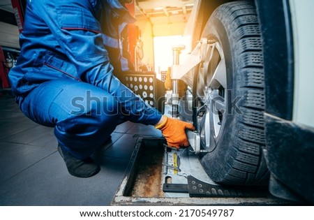 Auto mechanic installing sensor during suspension adjustment and automobile wheel alignment work at repair service station. Close up Royalty-Free Stock Photo #2170549787