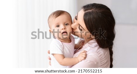 Happy mother kissing her cute little baby at home