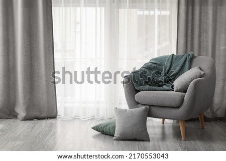 Comfortable grey armchair near cozy curtains in living room Royalty-Free Stock Photo #2170553043