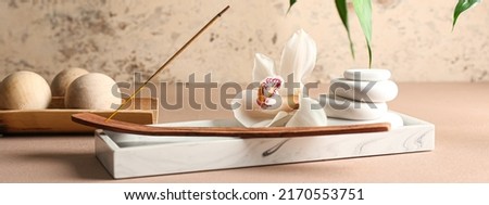 Beautiful spa composition with incense, flower and massage stones on table. Zen concept Royalty-Free Stock Photo #2170553751