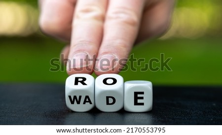 Symbol of the abortion process Roe versus Wade. Hand turns dice and changes the word Wade to Roe. Royalty-Free Stock Photo #2170553795